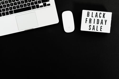 Free Black Friday sale sign with a laptop and mouse on a black background. Perfect for online shopping promotions. Stock Photo