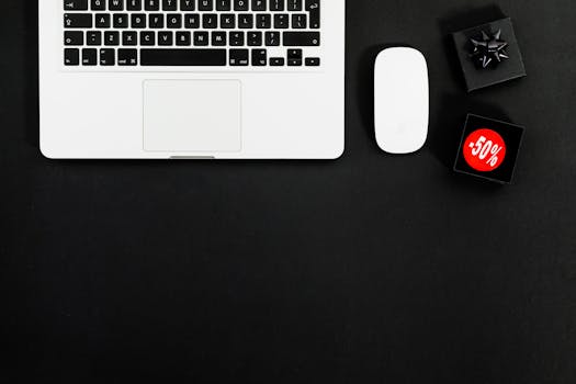 Minimalist flat lay featuring a laptop and shopping items with 50% sale tags.