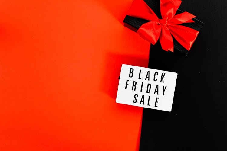 A Black Friday Sale Signage And Black Box Tied With Red Ribbon On Red And Black Background