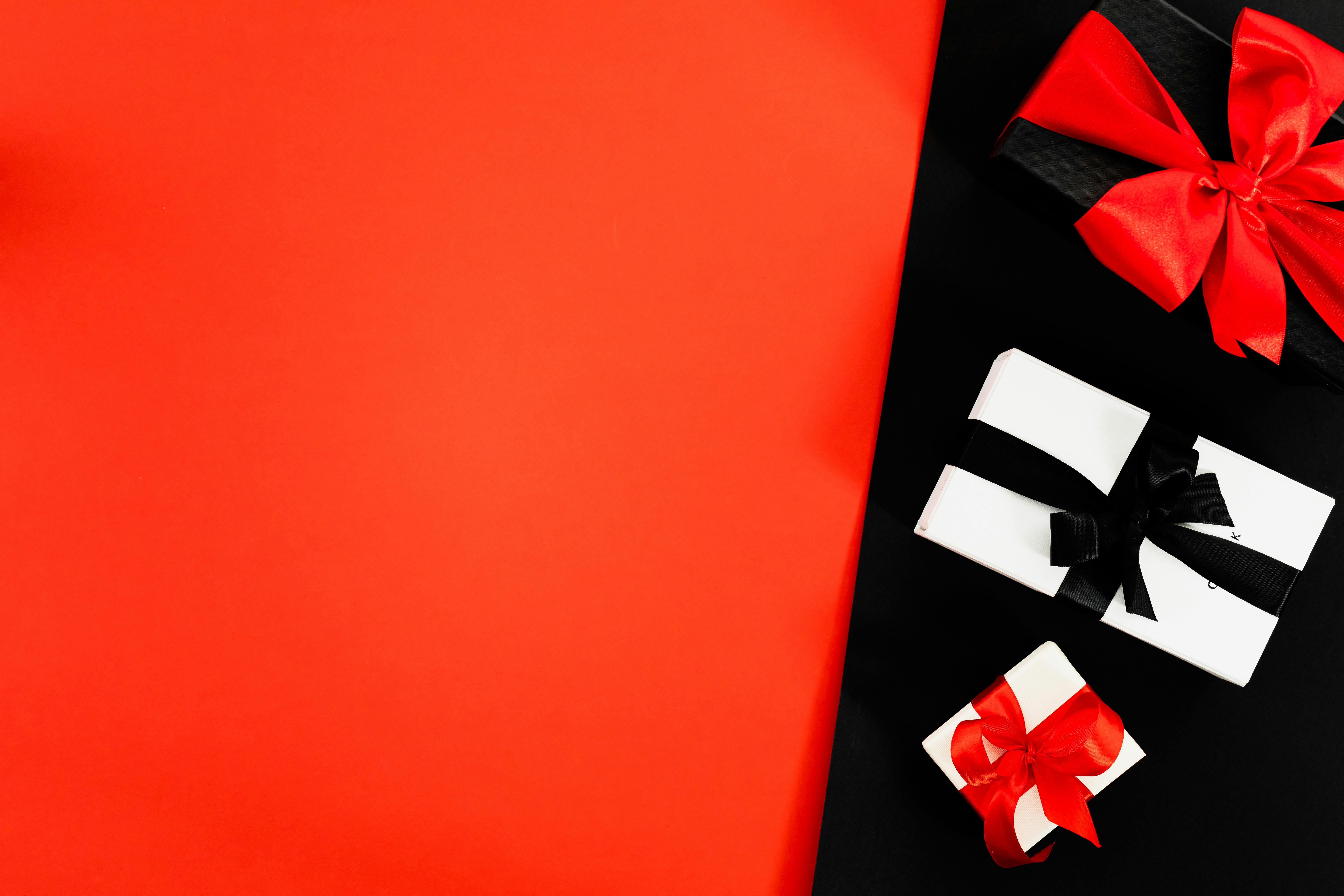 three boxes tied with ribbons on red and black background