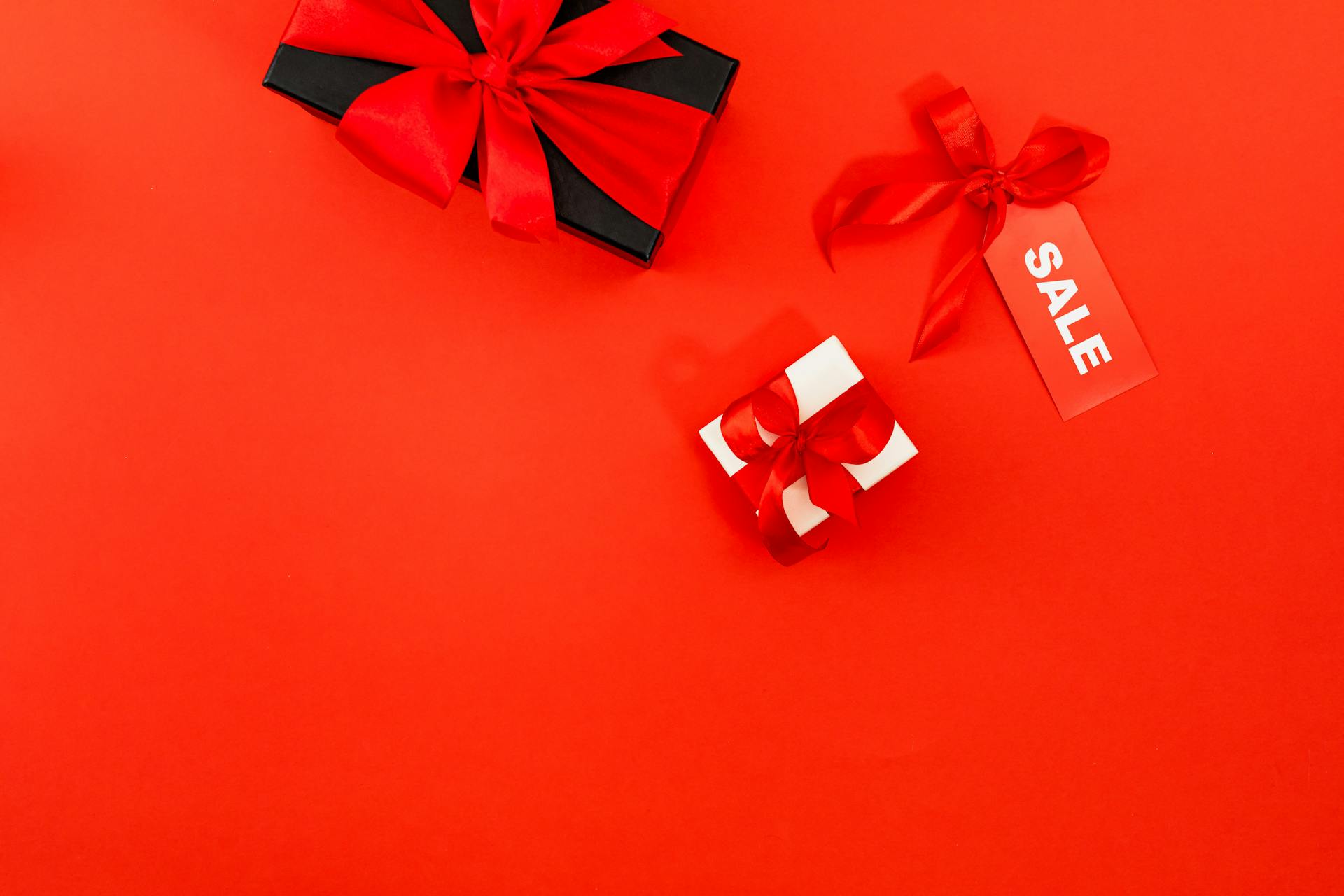 Vibrant red background with gift boxes and sale tag for promotional use.