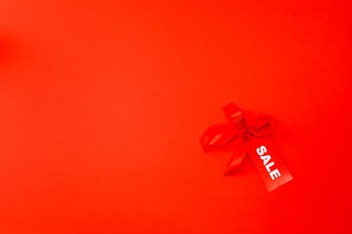A Red Ribbon and Sale Tag on Red Background
