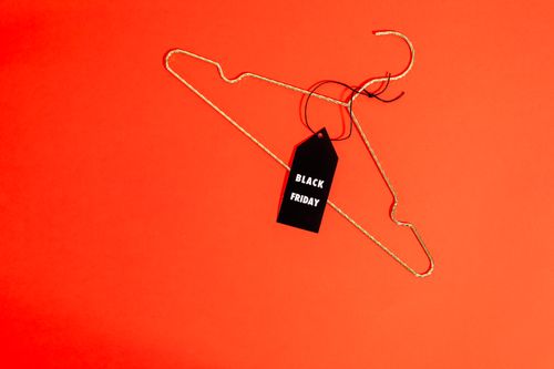 Free Gold wire hanger with Black Friday tag on red background. Perfect for sale promotions. Stock Photo