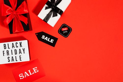 Free Flatlay of Black Friday sale gifts and tags on a red background with ample copy space. Stock Photo