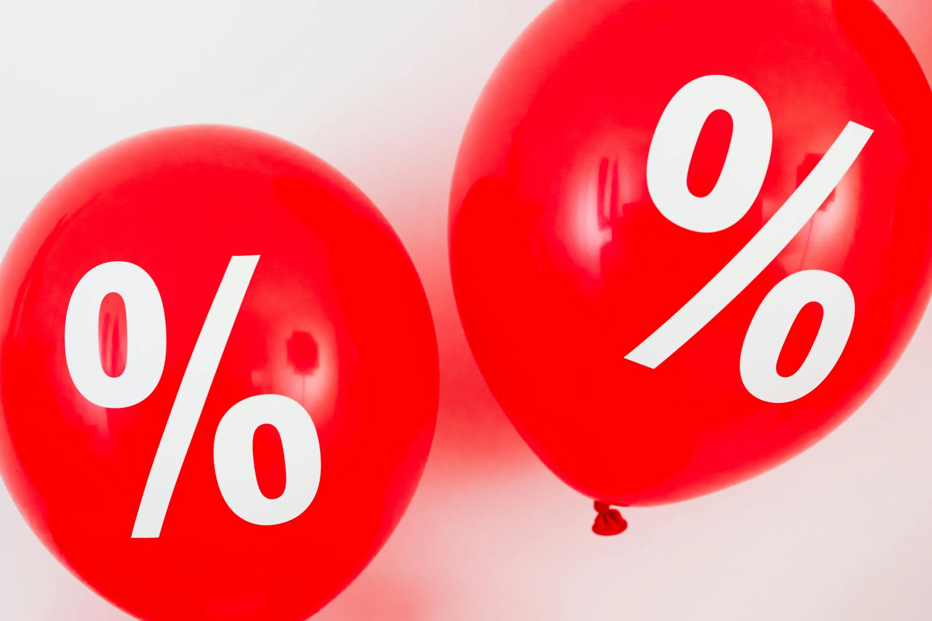 Two Red Balloons With Percentage Symbols on White Background