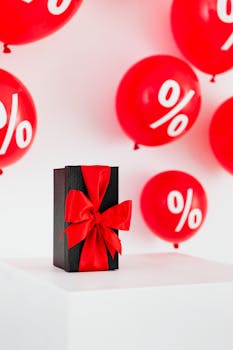 A black gift box with a red ribbon surrounded by red balloons displaying percentage signs.