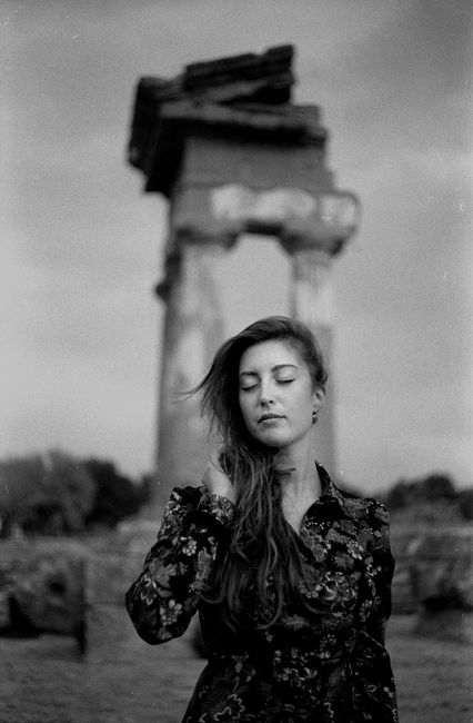 Black and white portrait of woman with eyes closed at ancient ruins in Agrigento, Sicily.