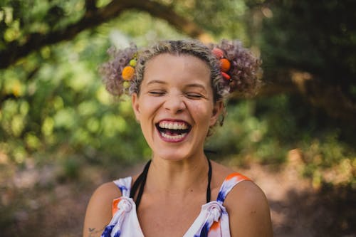 Excited young woman laughing with closed eyes in green garden