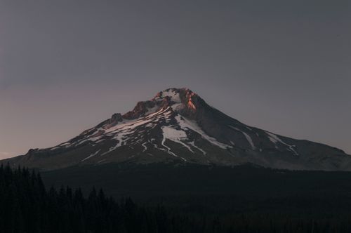 Free Dramatic view of Mount Hood's snowy peak against a gray sky during sunset. Stock Photo