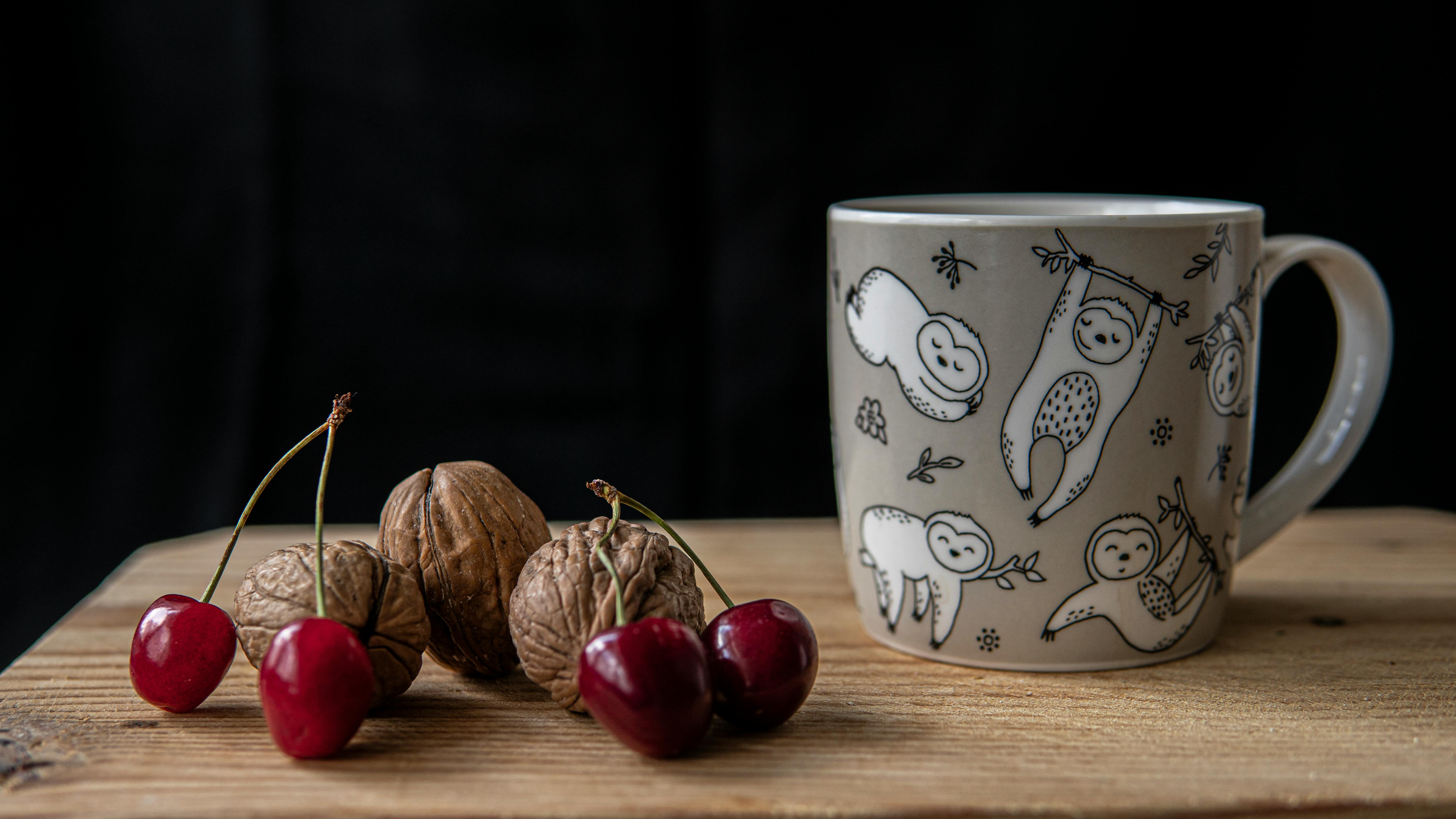 cup of hot drink near walnuts and cherries