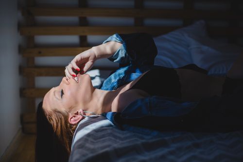 Free Side view of young seductive female with makeup and manicure in underwear resting on bed with closed eyes Stock Photo