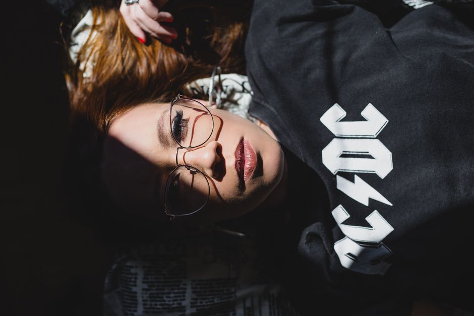 Top view of young attentive female in trendy apparel and eyewear with shade on face looking at camera