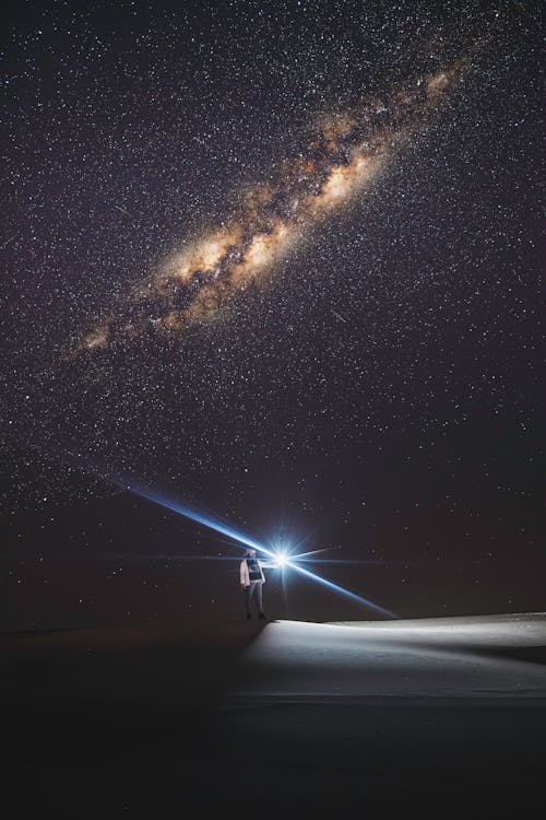 Free A Person with a Flashlight under a Starry Night Sky Stock Photo