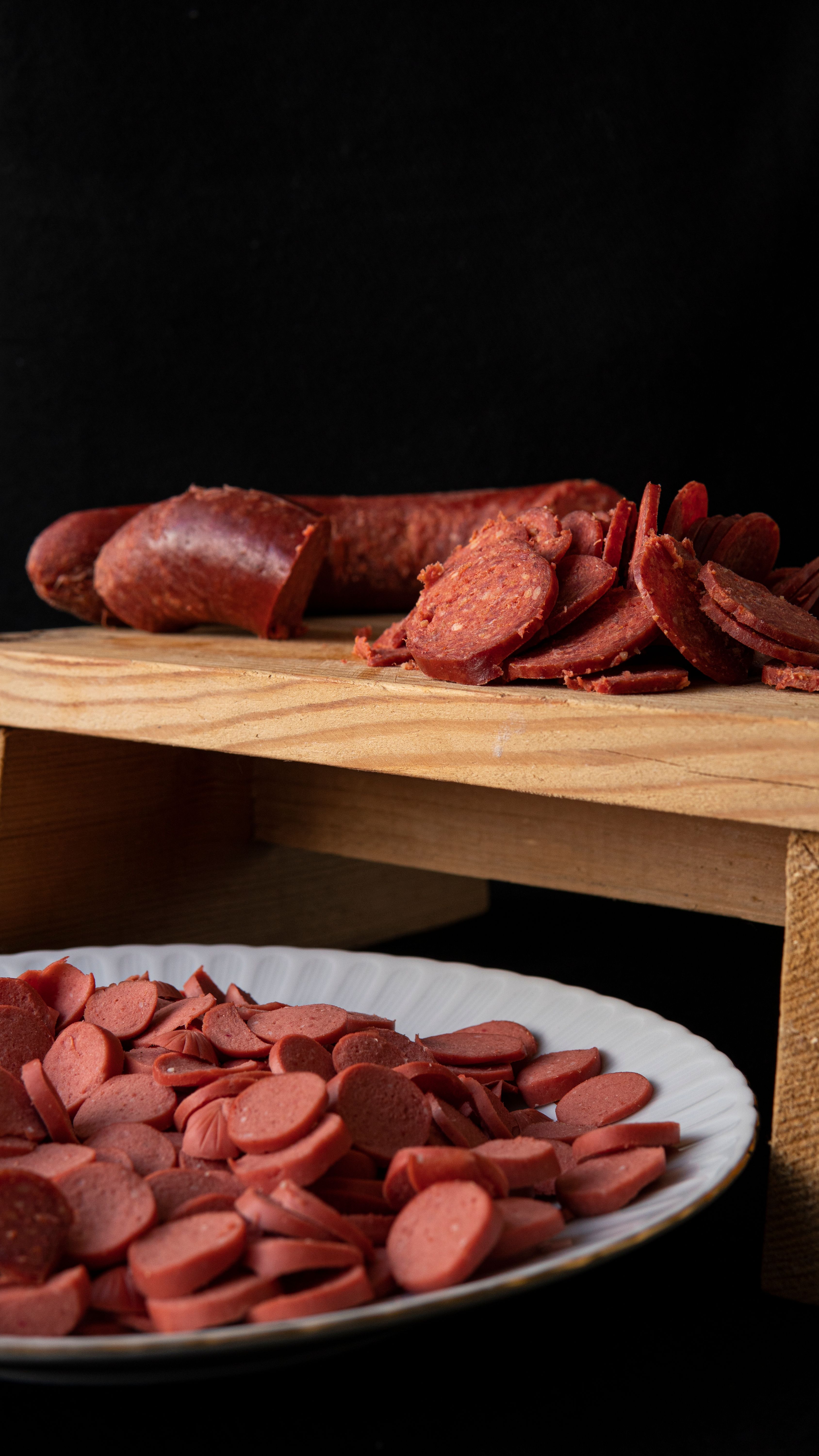 Tasty smoked sausage slices on black background