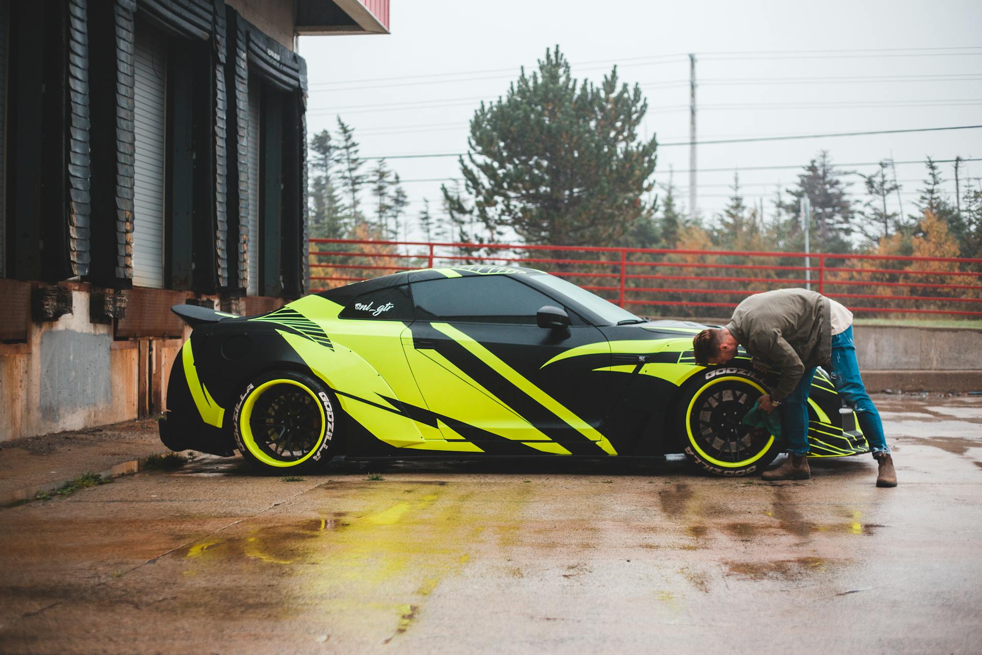 Unrecognizable man wiping wheel of car