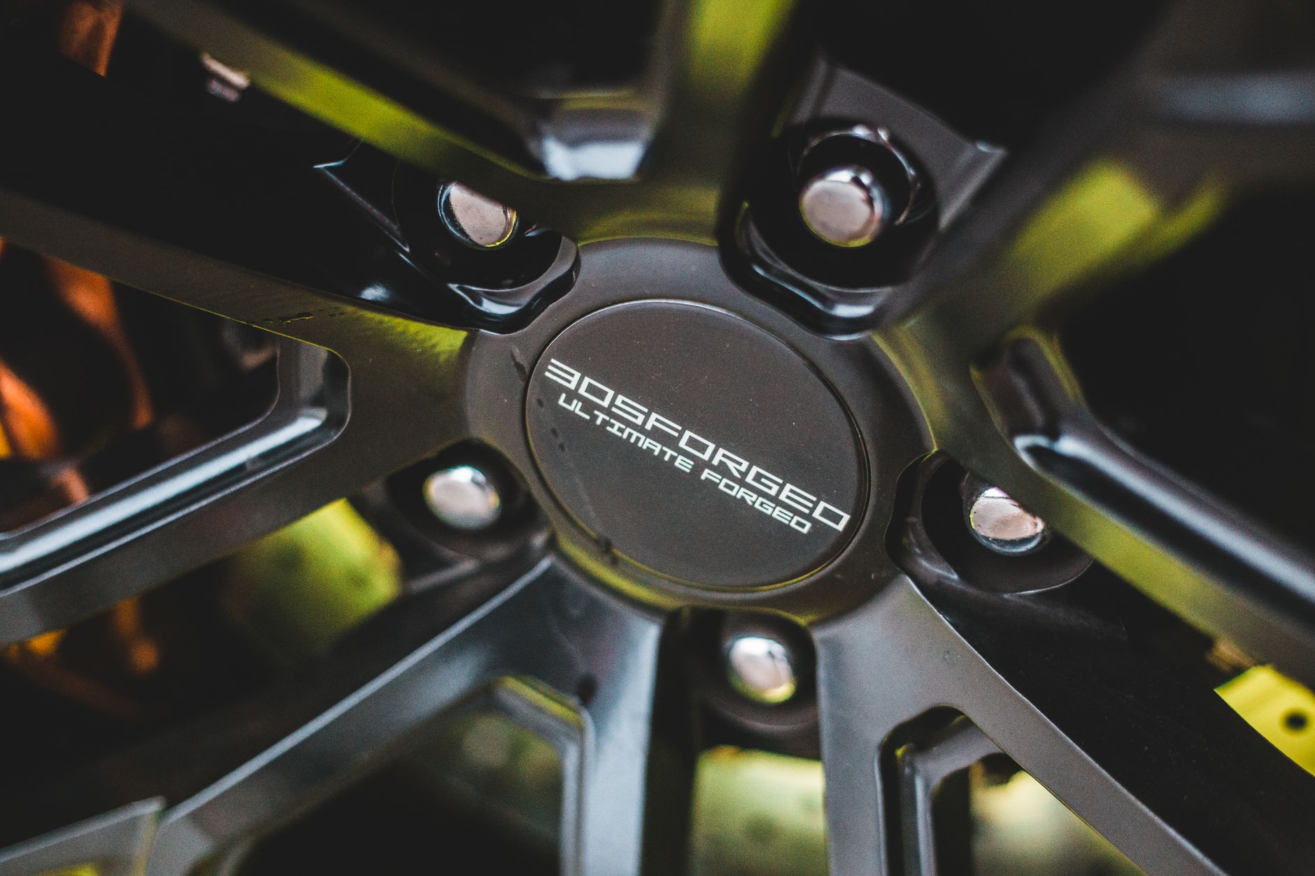 Closeup of new alloy wheel with silver screws in front of brake disc of sport automobile