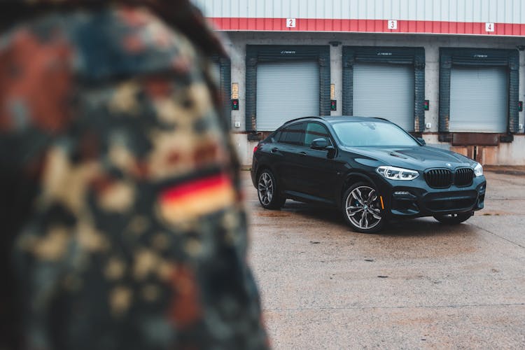 Crop Person In Camouflage Standing Near Car