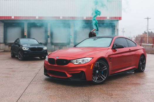 Unrecognizable man with smoking bomb behind car