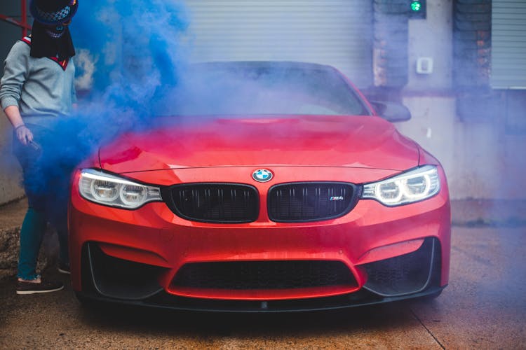 Female In Mystery Mask With Smoking Torch Near Modern Car