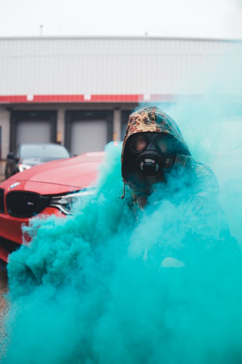 Free Person in Protective Gas Mask Covered with Colorful Smoke Stock Photo