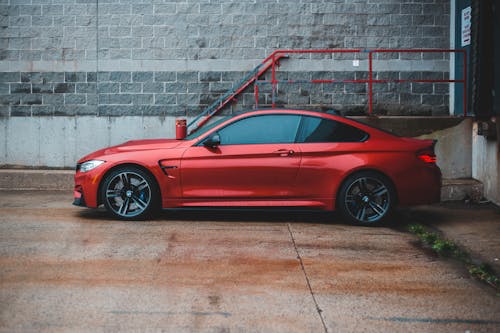 Red coupe car parked near shabby building