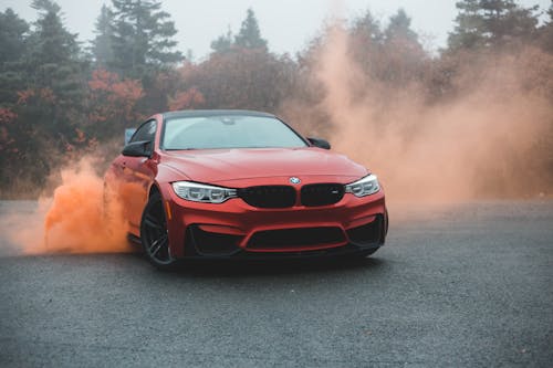 Free Luxury cool auto covered with colorful smoke on asphalt against autumn forest at daytime Stock Photo