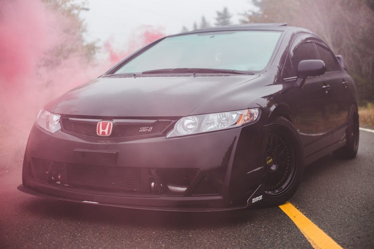 Black Car On Asphalt Road In Red Smoke