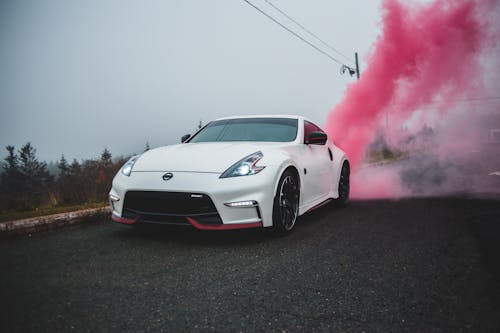 Contemporary white automobile with glossy surface and stylish headlights covered with colored smoke