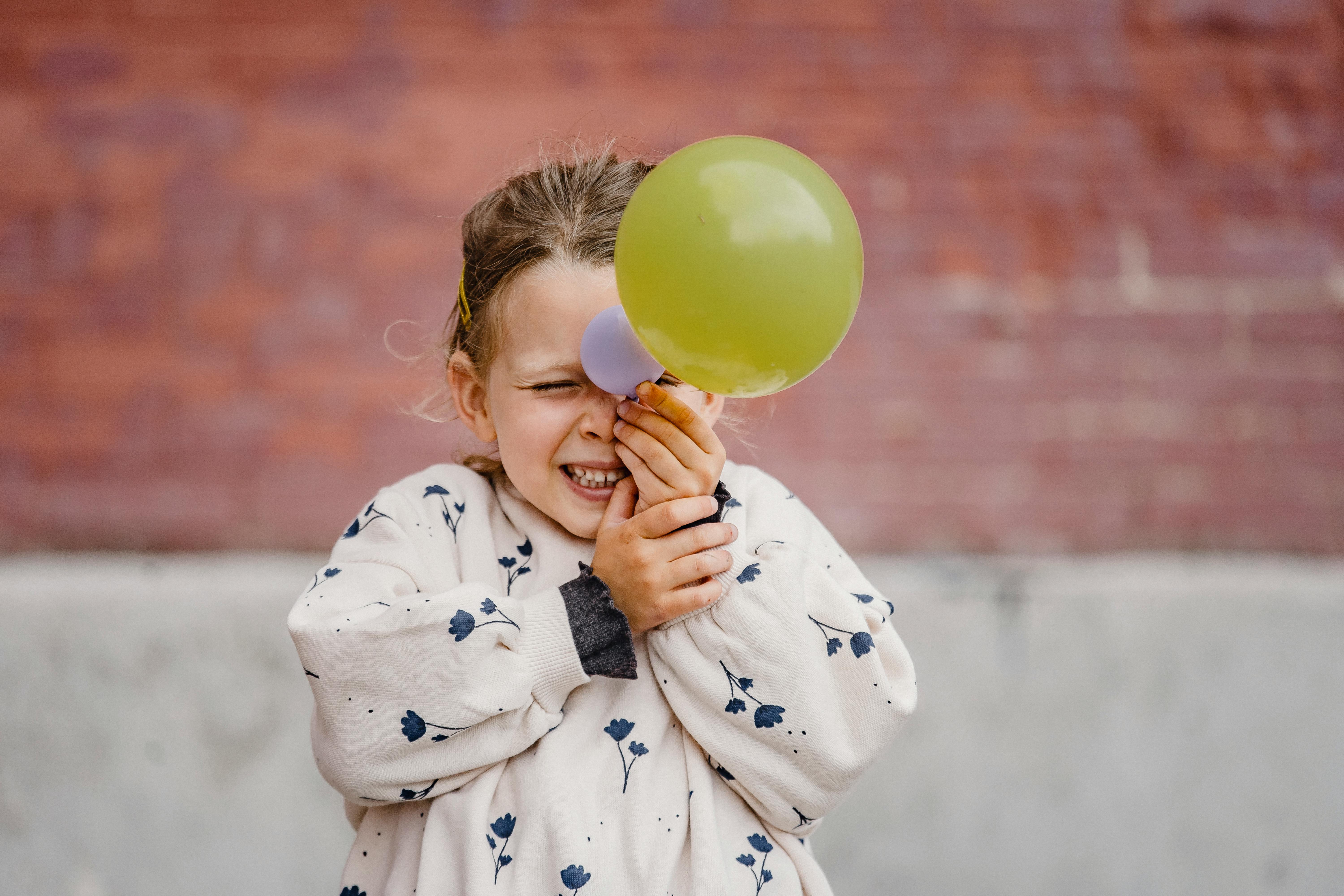 happy playful girl with balloon near building