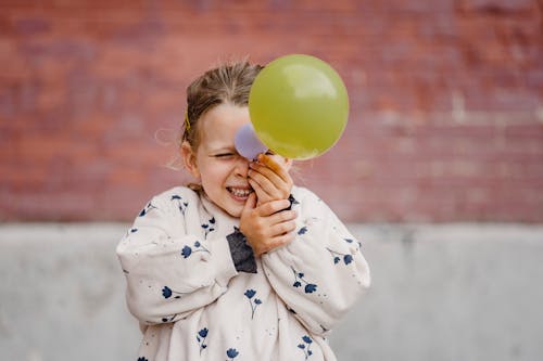Happy playful girl with balloon near building