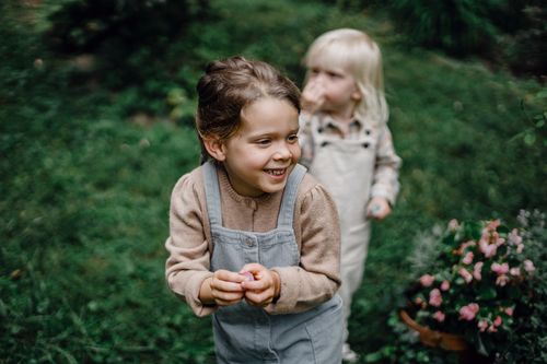 Free Content little kids wearing casual outfits standing together on grassy verdant meadow in summer park Stock Photo