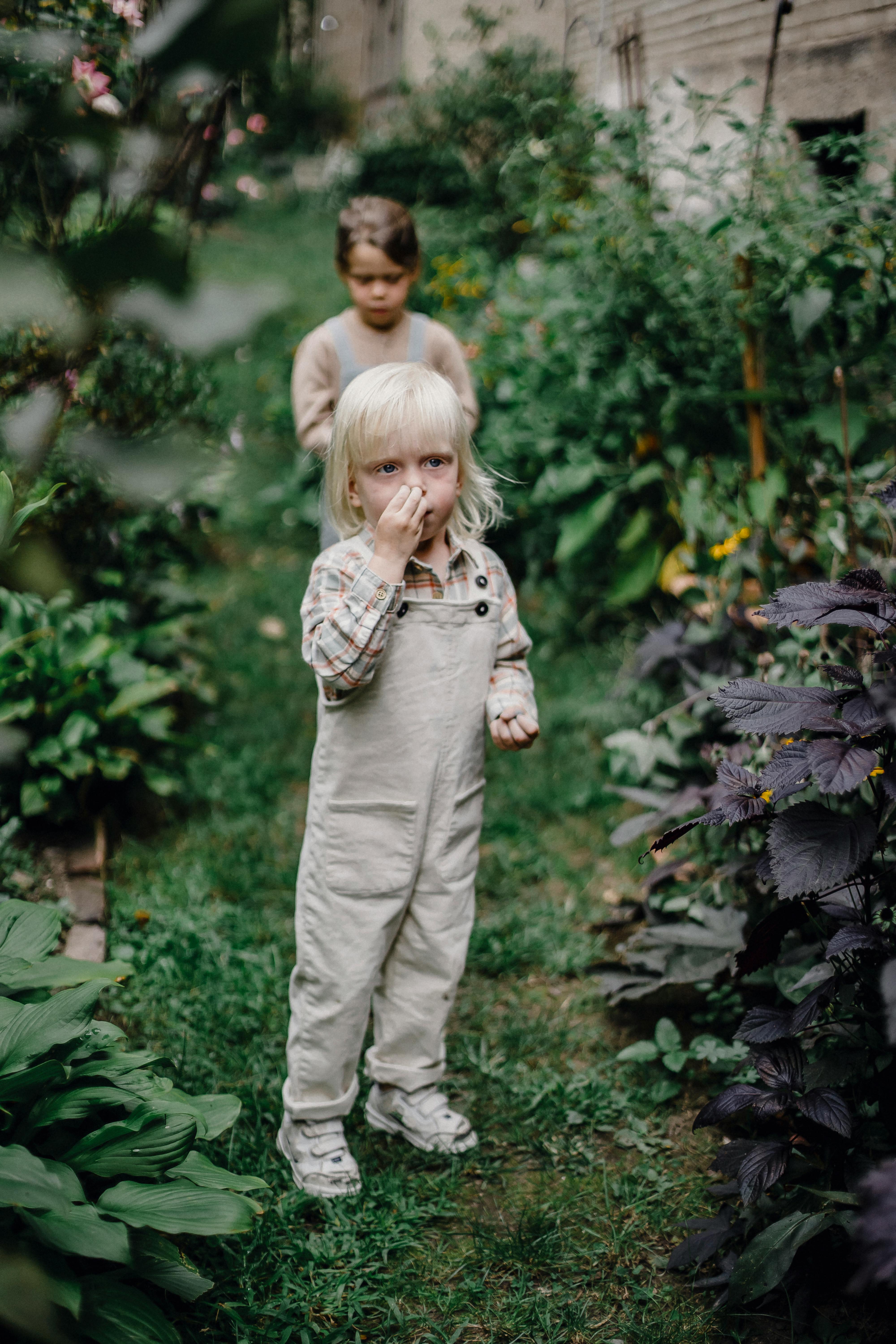 cute little sisters standing in lush park