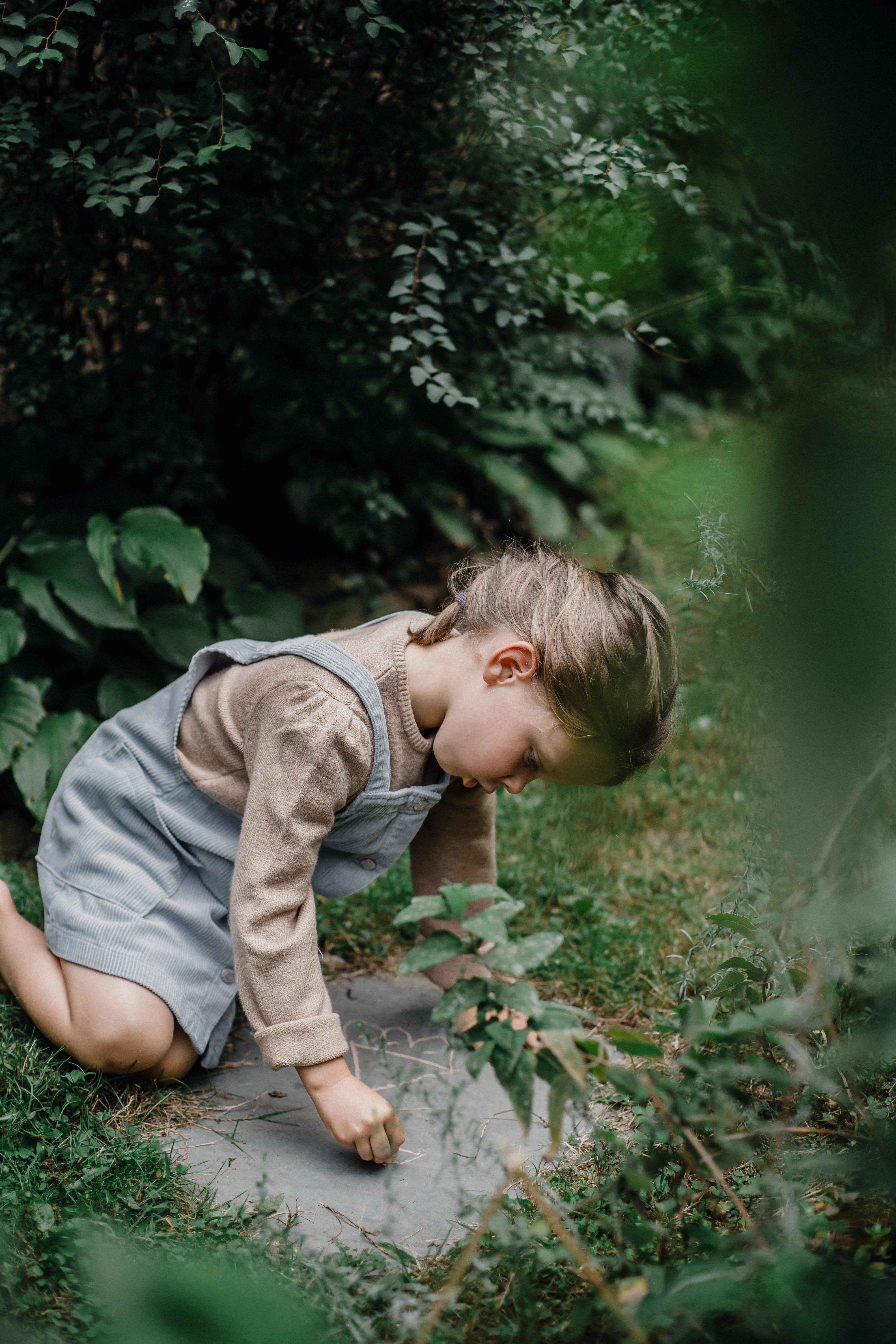 little girl with chalk drawing on stone in park