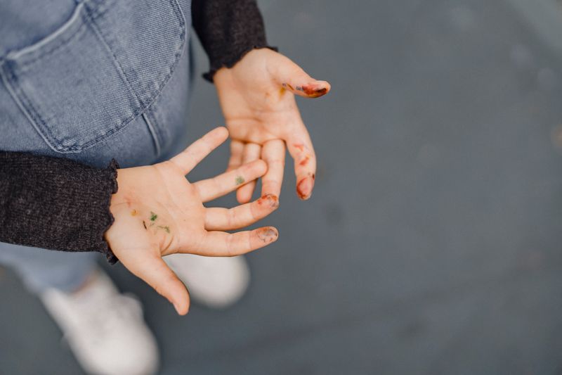 Child's hands covered in colorful paint