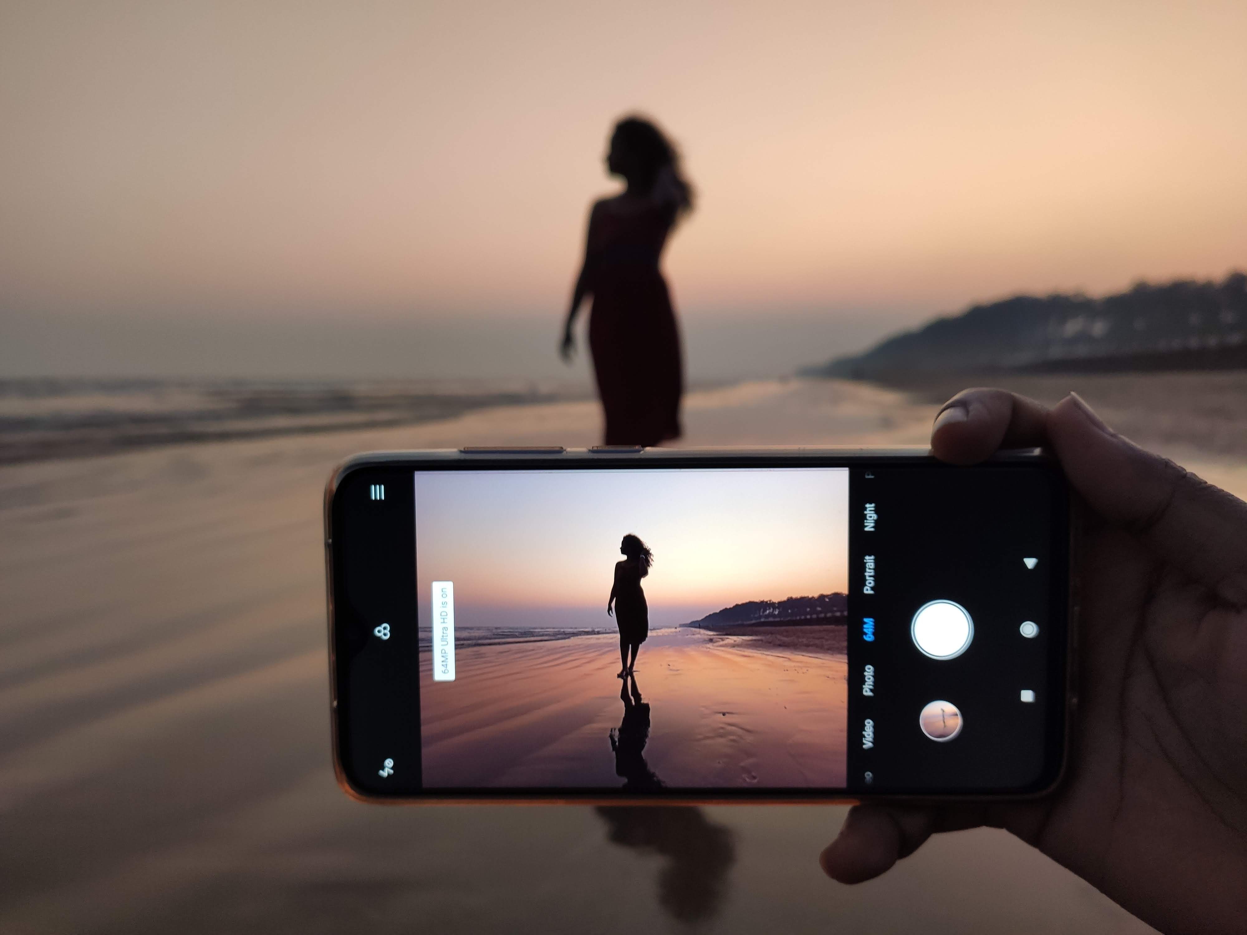 Silhouette of a woman at the beach captured during sunset using a smartphone.