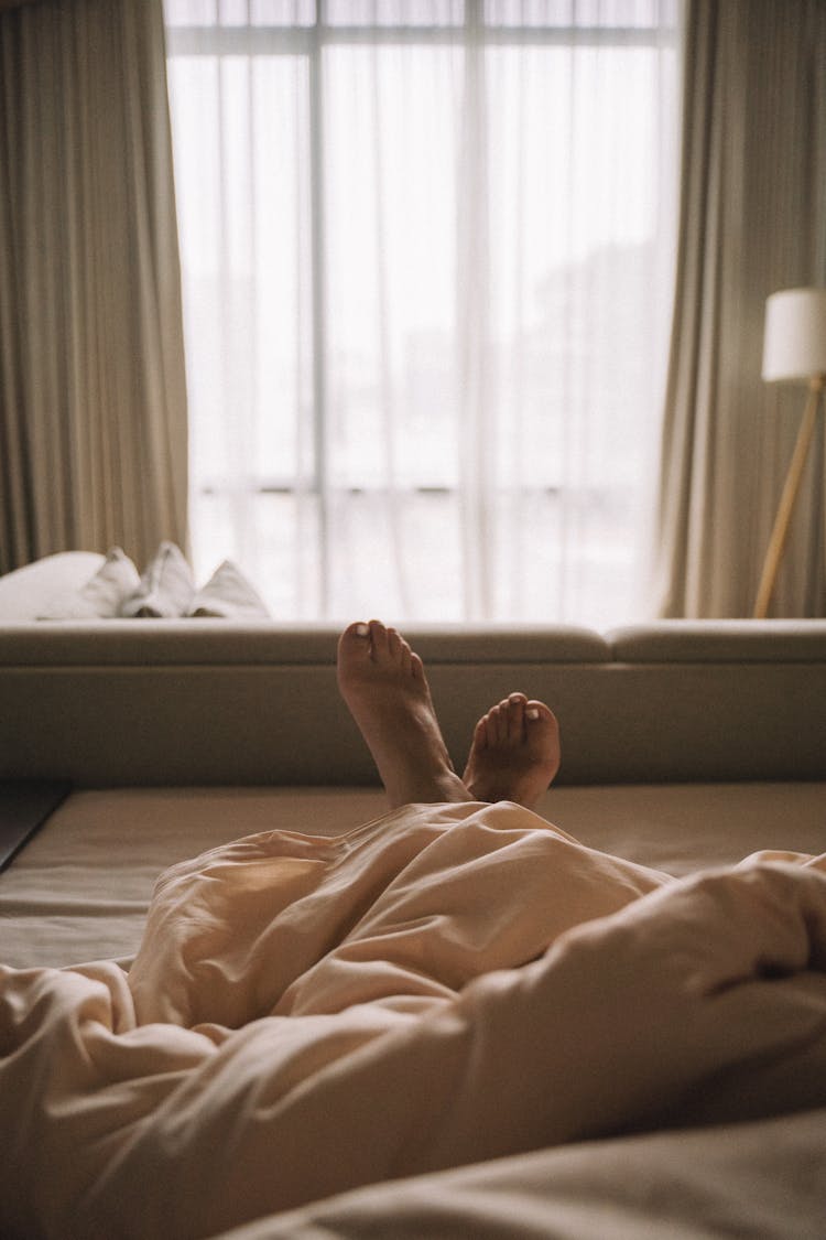 Feet Of A Person In Bed