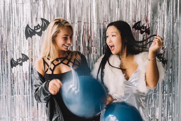 Women Standing In Front Of Foil Curtain While Holding Balloons