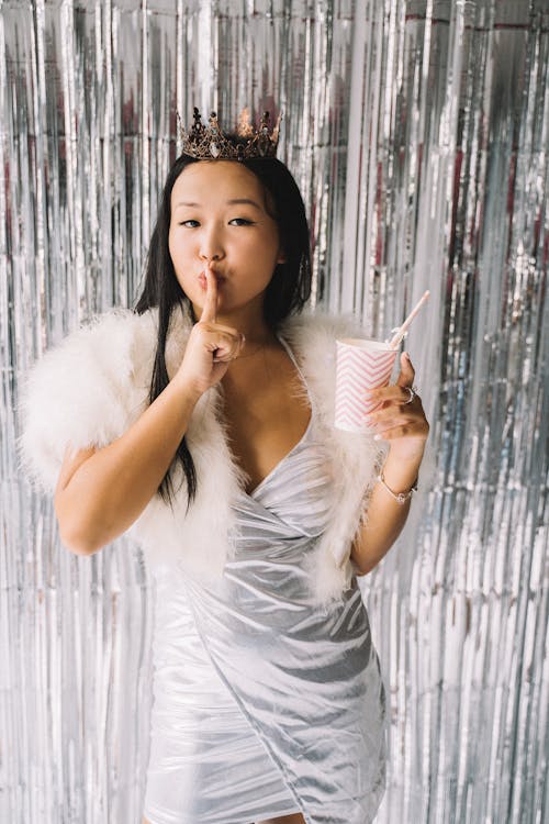 Woman in Silver Dress Standing in Front of Foil Curtain