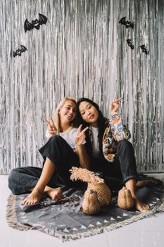 两名妇女在室内摆放万圣节装饰品，享受着节日的氛围