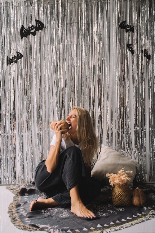 Photo of a Woman Sitting on the Floor while Holding a Pumpkin