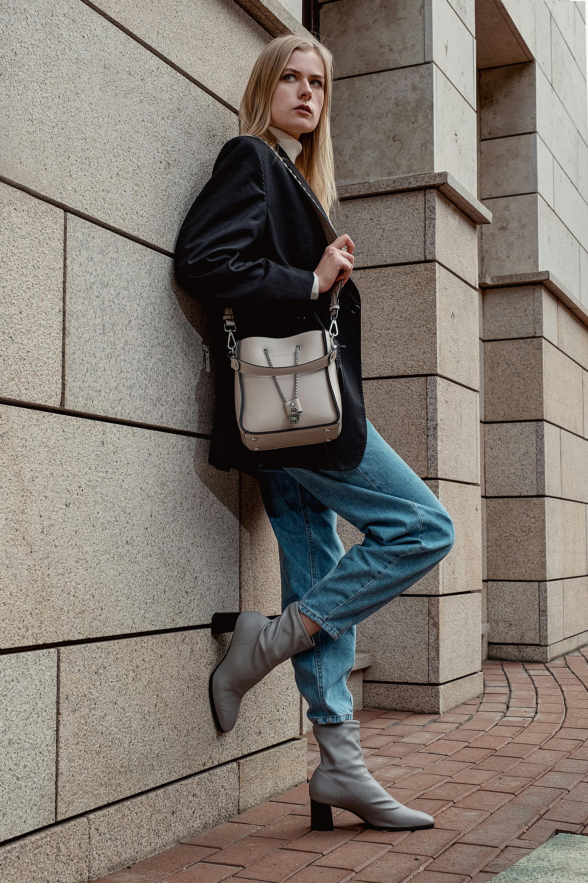 Unemotional stylish woman standing against modern building wall · Free