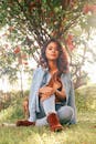 A Woman in Denim Clothes Sitting on Grass