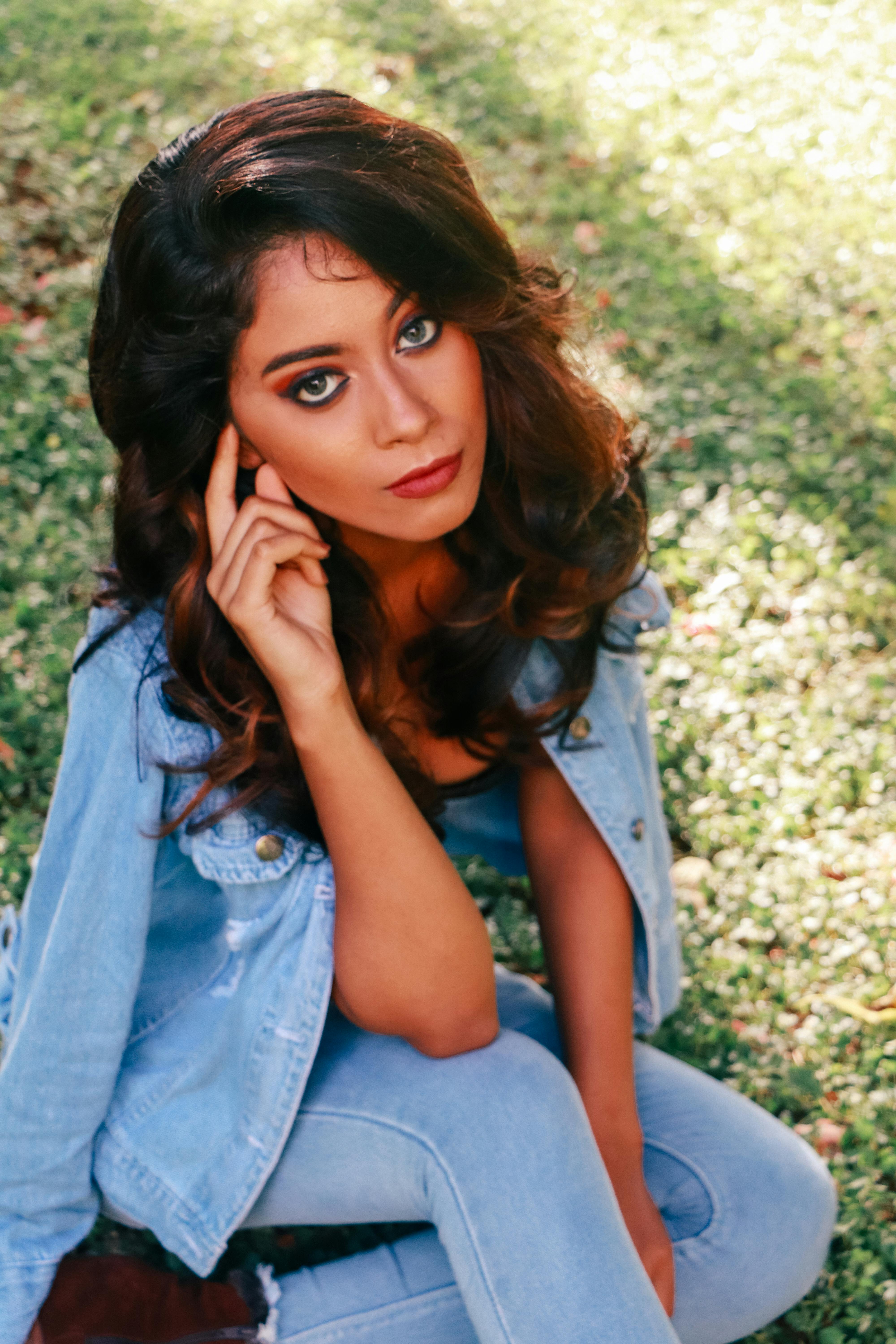 Stylish woman in denim sitting outdoors, showcasing modern fashion.