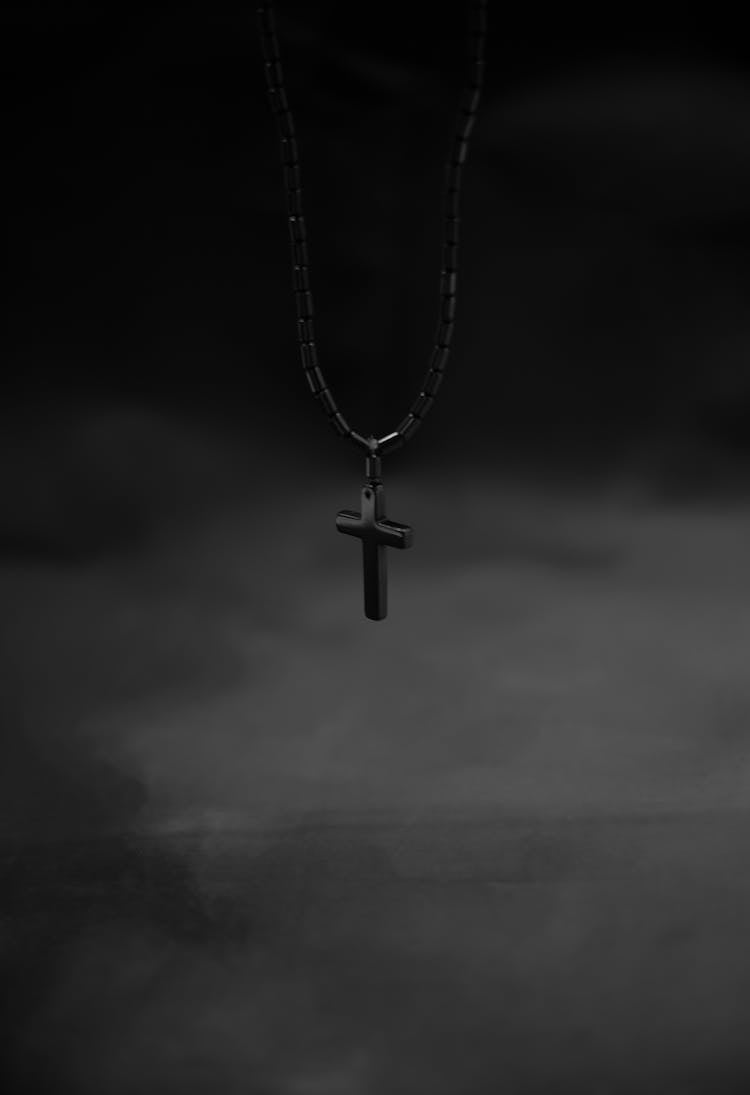 Grayscale Photo Of A Cross Pendant