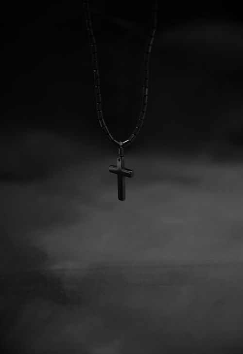 Free Elegant black cross pendant necklace on a chain in a minimalist grayscale composition. Stock Photo