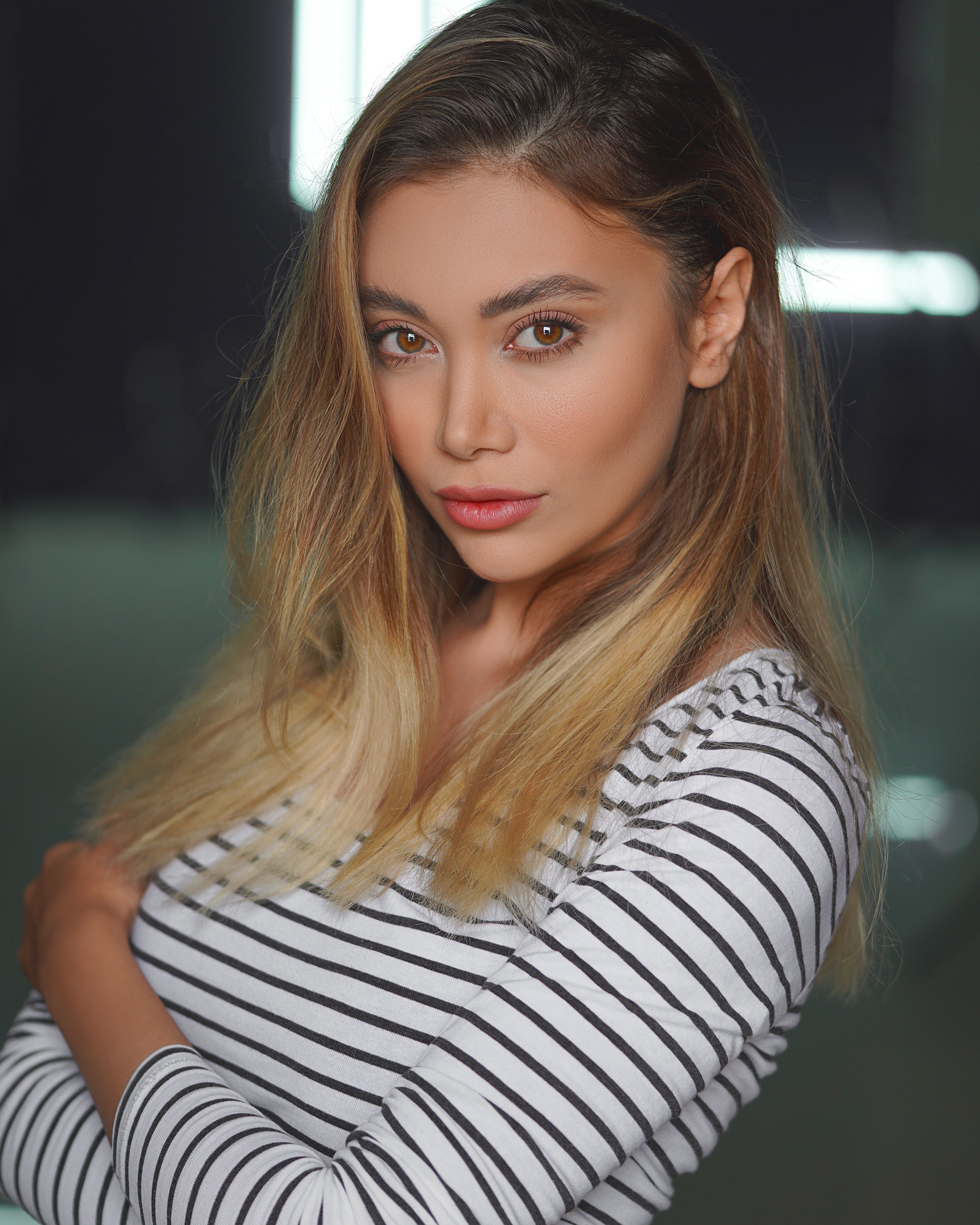 A striking portrait of a woman with blonde hair in a striped shirt showing confidence.