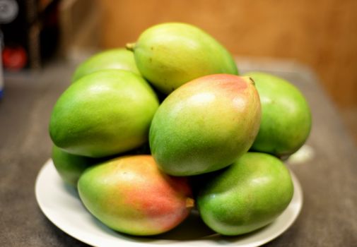 Vibrant green mangoes on a white plate, showcasing freshness and juiciness.