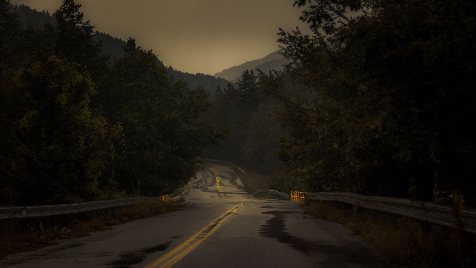 Carretera de montaña al amanecer, con niebla sobre las laderas