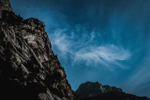 Low angle of spectacular landscape with rough rocky mountains under bright blue sky in sunlight