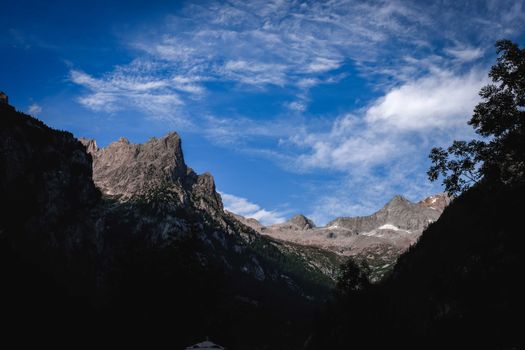 Scenery view of rough mountains with dry surface and growing trees under bright sky in summer